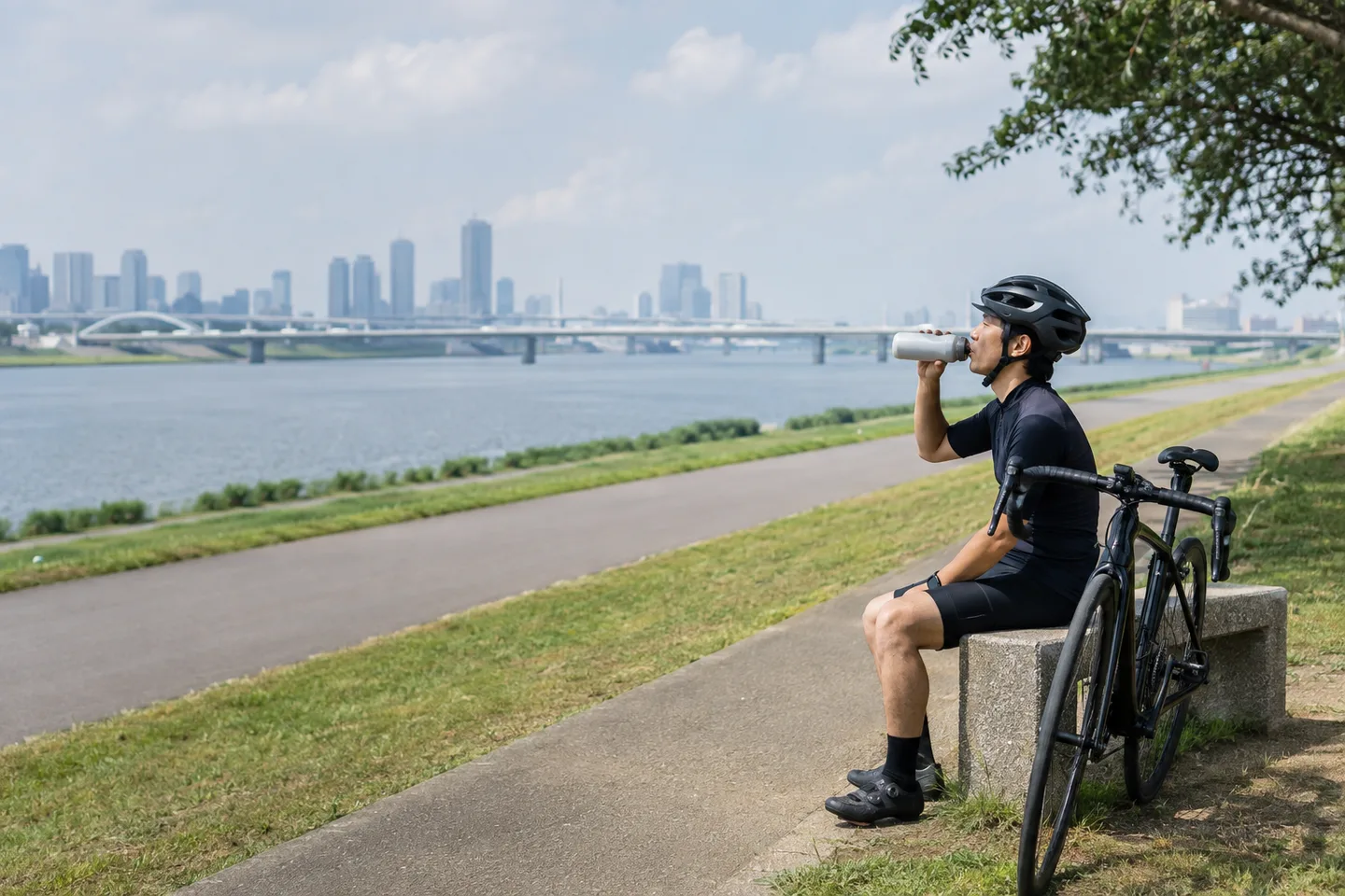 荒川沿いでロードバイクを安全な場所へ止め、水分補給するイメージ。特定の施設を示すものではありません